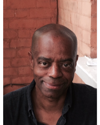 Head and shoulders image of Mike Bryant directly facing the camera in front of red brick and a white windowsill