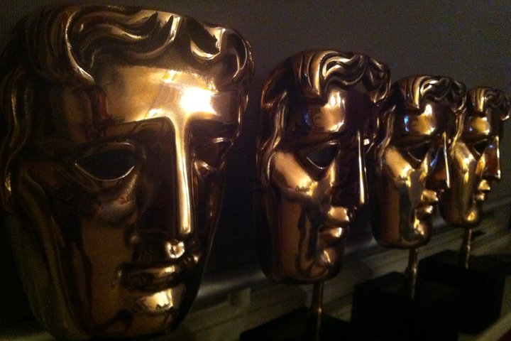 © Laura Thorne Four shining gold BAFTA awards lined up in dark lighting