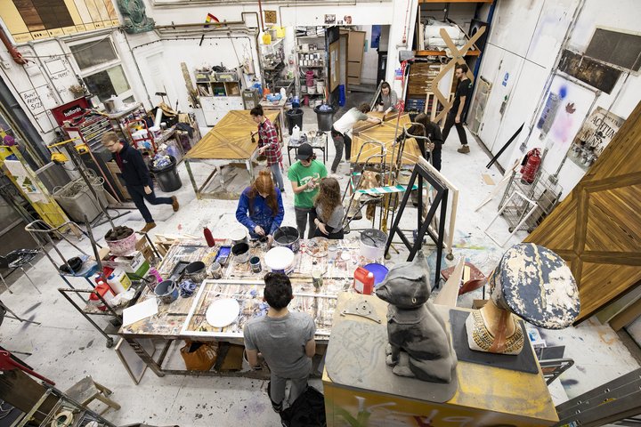 A birds eye view of a busy scenic art workshop, with students mixing paint and working on creating a replica parquet floor